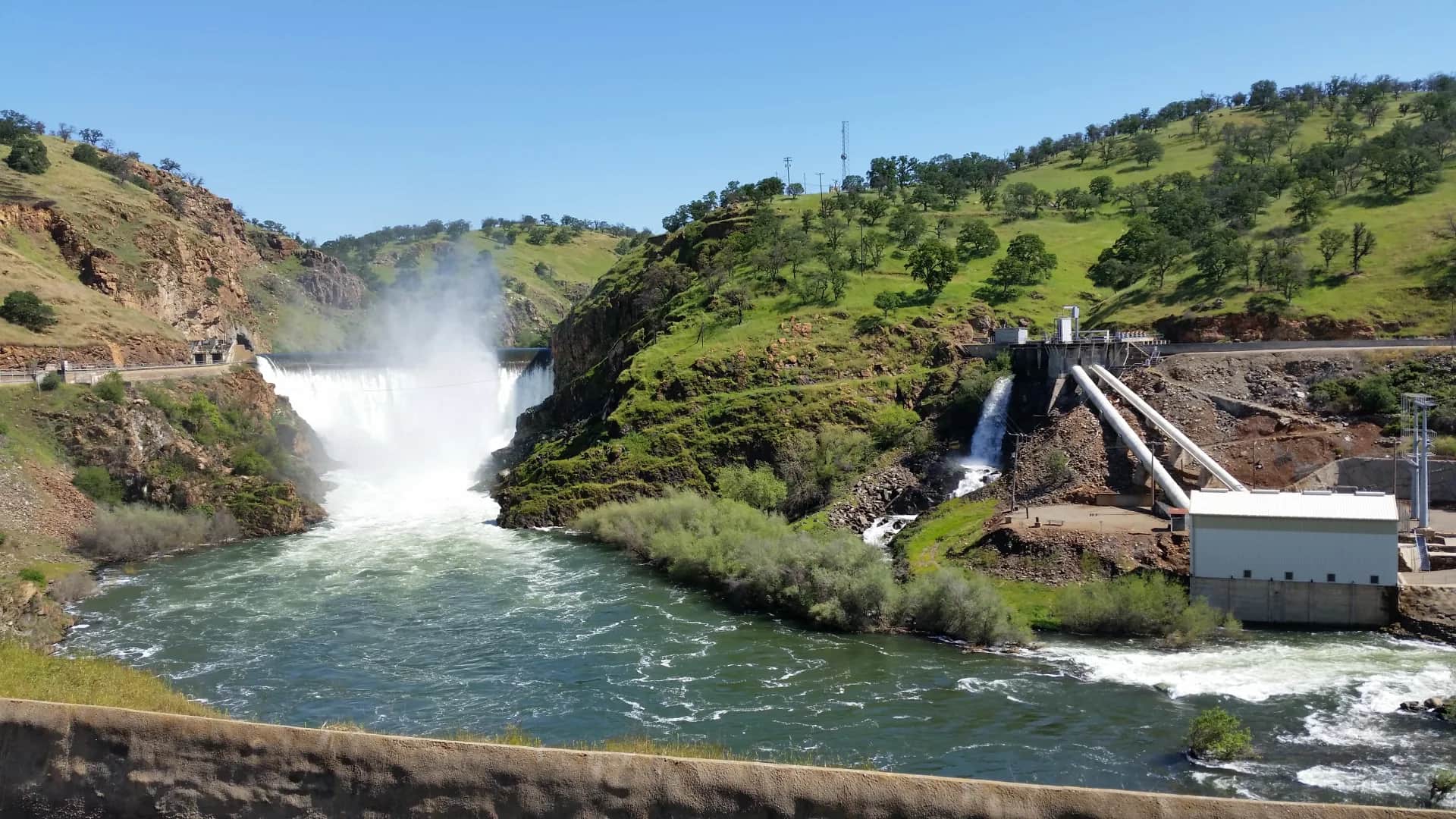 Historical April 2017 view of the Tuolumne River below La Grange Dam at USGS gage 11289650, with dam spillways and green foothills.